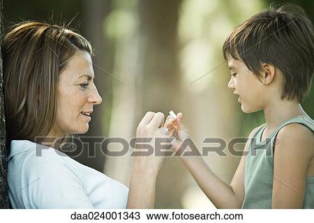Mother and son sitting outdoors, playing together View Large Photo Image Stock Image - Mother and son sitting outdoors, playing together. Fotosearch