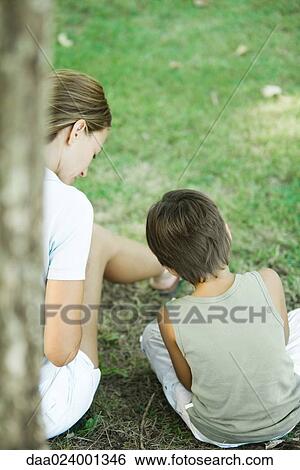 Stock Photograph - Mother and son sitting outdoors, playing together, rear view. Fotosearch