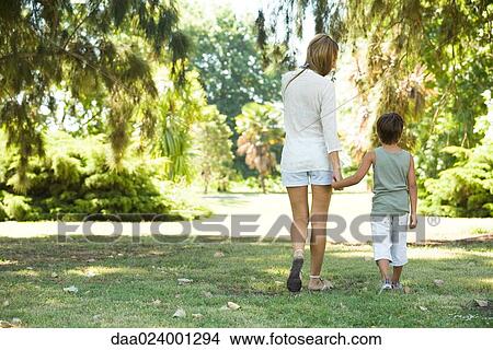 Mother and son, walking hand in hand, rear view View Large Photo Image Picture - Mother and son, walking hand in hand, rear view. Fotosearch