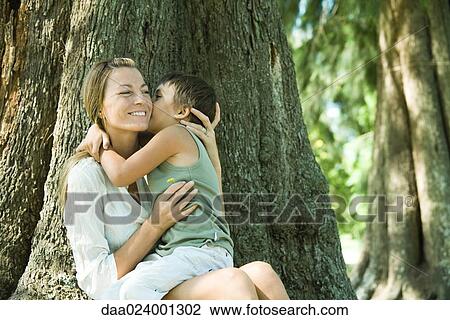 Mother and son, woman holding flower, boy kissing her cheek View Large Photo Image Stock Image - Mother and son, woman holding flower, boy kissing her cheek. Fotosearch