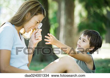 Mother and son, woman looking through magnifying glass while boy reaches for it View Large Photo Image Picture - Mother and son, woman looking through magnifying glass while boy reaches for it. Fotosearch