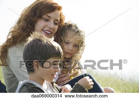 Mother and two children relaxing together outdoors View Large Photo Image Picture - Mother and two children relaxing together outdoors. Fotosearch