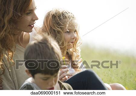 Stock Image - Mother and two children relaxing together outdoors. Fotosearch