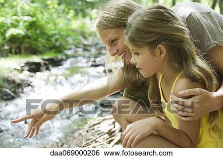 Stock Photograph - Mother and young daughter looking at stream together. Fotosearch