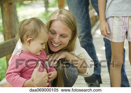Stock Photography - Mother crouching beside baby outdoors. Fotosearch