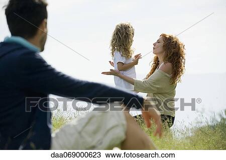Mother talking with young daughter outdoors, father watching from foreground View Large Photo Image Stock Image - Mother talking with young daughter outdoors, father watching from foreground. Fotosearch