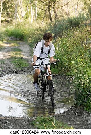 Picture - Mountain biker riding through puddle. Fotosearch