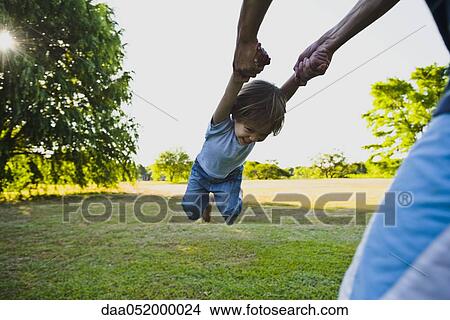 Parent spinning little boy in park View Large Photo Image Picture - Parent spinning little boy in park. Fotosearch
