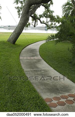 Stock Image - Paved path in waterside park. Fotosearch