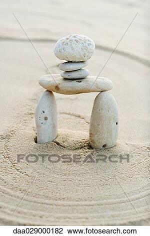Stock Image - Pebbles and coral stacked in sand, close-up. Fotosearch