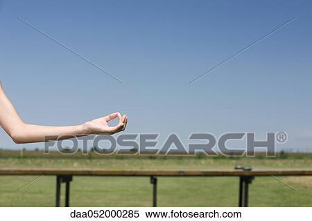 Stock Photography - Person meditating outdoors, cropped view of arm in mudra position. Fotosearch