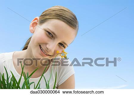 Preteen girl leaning cheek against flower View Large Photo Image Picture - Preteen girl leaning cheek against flower. Fotosearch