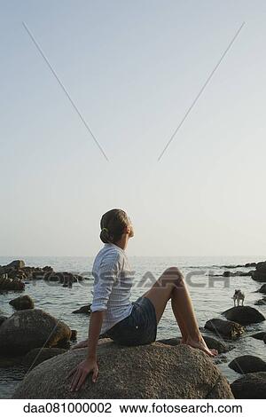 Preteen girl relaxing on rock, enjoying view of ocean View Large Photo Image Stock Image - Preteen girl relaxing on rock, enjoying view of ocean. Fotosearch