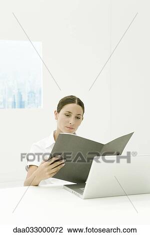 Professional woman looking at document, sitting at desk View Large Photo Image Stock Image - Professional woman looking at document, sitting at desk. Fotosearch