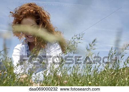Redheaded woman in grass View Large Photo Image Stock Image - Redheaded woman in grass. Fotosearch