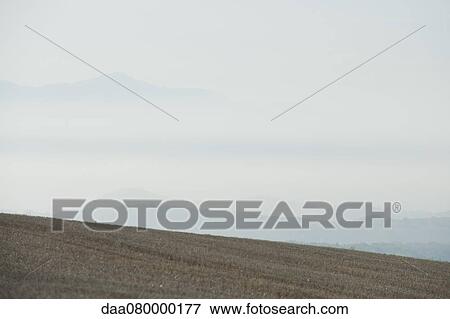 Rural field with fog and mountains in the distance View Large Photo Image Stock Photo - Rural field with fog and mountains in the distance. Fotosearch