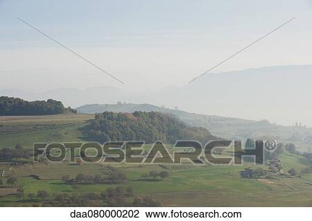 Stock Image - Rural landscape with fog and mountains in the distance. Fotosearch