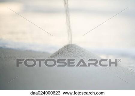 Stock Image - Sand falling onto pile on beach. Fotosearch