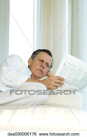 Senior man reclining, reading newspaper View Large Photo Image Stock Photograph - Senior man reclining, reading newspaper. Fotosearch