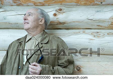 Senior man standing next to log cabin View Large Photo Image Stock Image - Senior man standing next to log cabin. Fotosearch