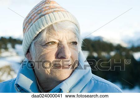 Stock Image - Senior woman in snowy landscape, head and shoulders. Fotosearch