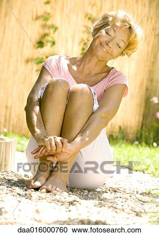 Senior woman sitting on ground outdoors, eyes closed, smiling View Large Photo Image Stock Image - Senior woman sitting on ground outdoors, eyes closed, smiling. Fotosearch