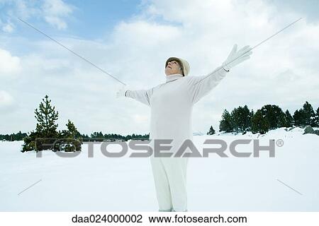 Senior woman standing on snow, arms out, looking up, low angle view View Large Photo Image Stock Image - Senior woman standing on snow, arms out, looking up, low angle view. Fotosearch