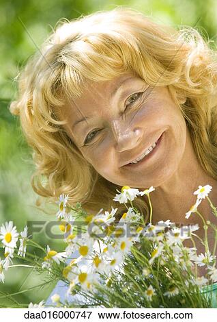 Stock Photo - Senior woman with daisies, smiling. Fotosearch