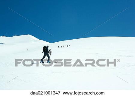 Skier going across snowy landscape, looking toward group of skiers in distance View Large Photo Image Stock Photo - Skier going across snowy landscape, looking toward group of skiers in distance. Fotosearch