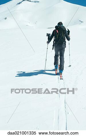 Stock Photography - Skier heading toward mountain, rear view. Fotosearch