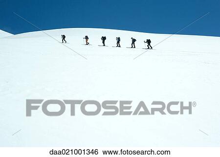 Skiers going across snowy landscape, single file View Large Photo Image Stock Photograph - Skiers going across snowy landscape, single file. Fotosearch