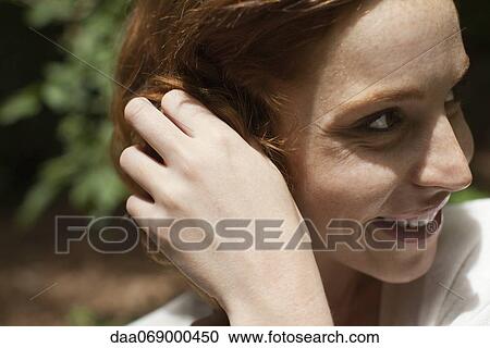 Smiling young woman with hand in hair, side view View Large Photo Image Stock Image - Smiling young woman with hand in hair, side view. Fotosearch