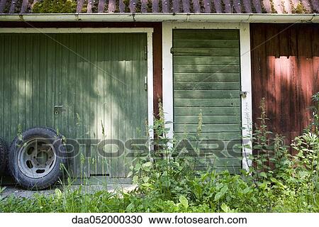 Stock Image - Spare tire leaning against garage door. Fotosearch