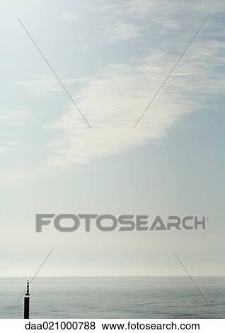 Stones stacked on wooden pole in body of water View Large Photo Image Stock Photo - Stones stacked on wooden pole in body of water. Fotosearch
