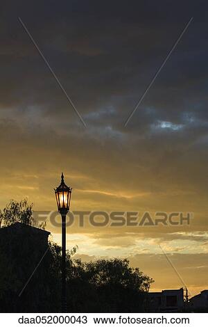Stock Image - Street lamp illuminated at dusk. Fotosearch