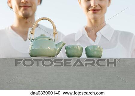 Teapot and tea cups sitting on ledge, cropped view of man and woman waiting nearby View Large Photo Image Stock Image - Teapot and tea cups sitting on ledge, cropped view of man and woman waiting nearby. Fotosearch