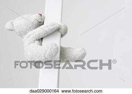 Teddy bear holding on to pole, close-up View Large Photo Image Picture - Teddy bear holding on to pole, close-up. Fotosearch