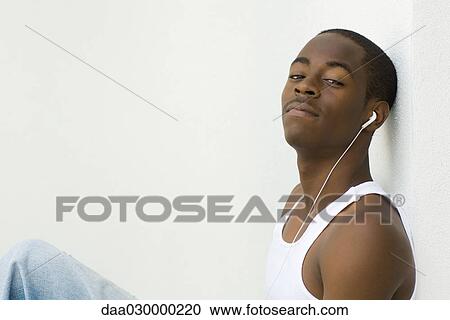 Teen boy listening to earphones, looking at camera View Large Photo Image Stock Image - Teen boy listening to earphones, looking at camera. Fotosearch