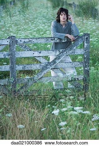 Teen boy listening to earphones, leaning against wooden fence View Large Photo Image Stock Photograph - Teen boy listening to earphones, leaning against wooden fence. Fotosearch