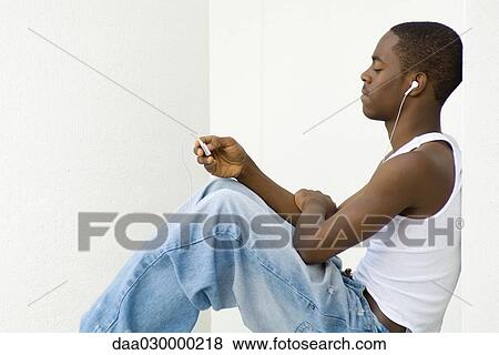 Teen boy sitting, listening to MP3 player, side view View Large Photo Image Stock Photo - Teen boy sitting, listening to MP3 player, side view. Fotosearch