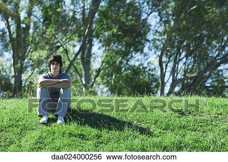 Teen boy sitting on grassy hill, relaxing View Large Photo Image Stock Photograph - Teen boy sitting on grassy hill, relaxing. Fotosearch