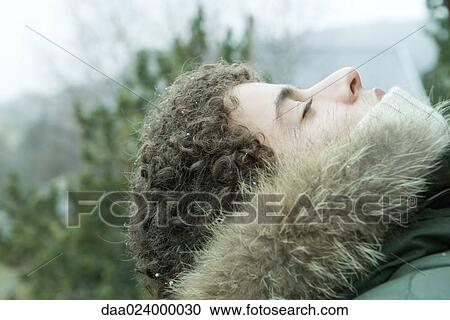 Stock Image - Teen boy wearing parka, head back and eyes closed. Fotosearch
