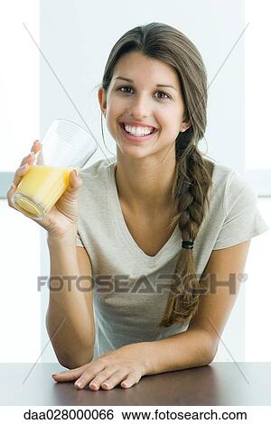 Teen girl drinking glass of orange juice, smiling at camera View Large Photo Image Stock Photograph - Teen girl drinking glass of orange juice, smiling at camera. Fotosearch