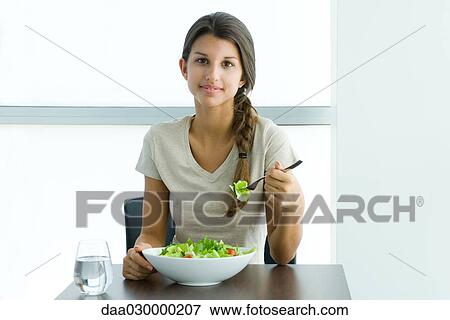 Stock Photo - Teen girl eating salad, smiling at camera. Fotosearch