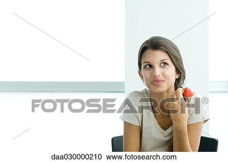 Teen girl holding strawberry, looking away View Large Photo Image Stock Image - Teen girl holding strawberry, looking away. Fotosearch
