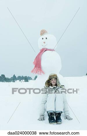 Stock Photo - Teen girl leaning against snowman. Fotosearch