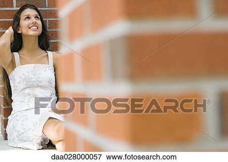 Teen girl sitting on ground, leaning against brick wall, looking up, smiling View Large Photo Image Stock Photo - Teen girl sitting on ground, leaning against brick wall, looking up, smiling. Fotosearch