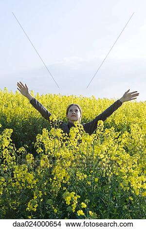 Picture - Teen girl standing in field of canola in bloom. Fotosearch