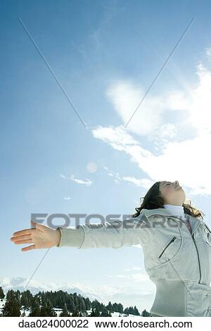 Teen girl standing in snowy landscape with head back and arms out, low angle view View Large Photo Image Stock Image - Teen girl standing in snowy landscape with head back and arms out, low angle view. Fotosearch