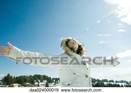 Teen girl standing in snowy landscape with arms out, head back, low angle view View Large Photo Image Stock Photo - Teen girl standing in snowy landscape with arms out, head back, low angle view. Fotosearch